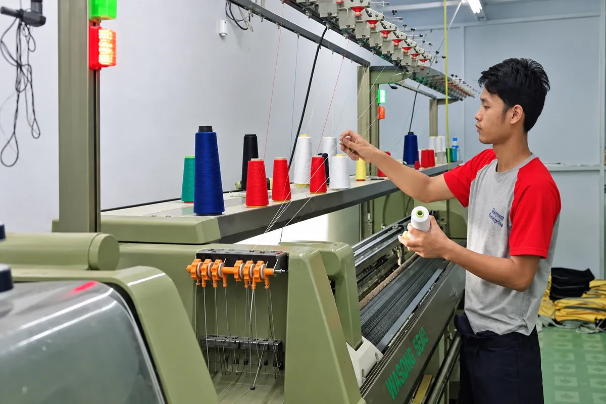 Technician loading thread on a collar knitting machine