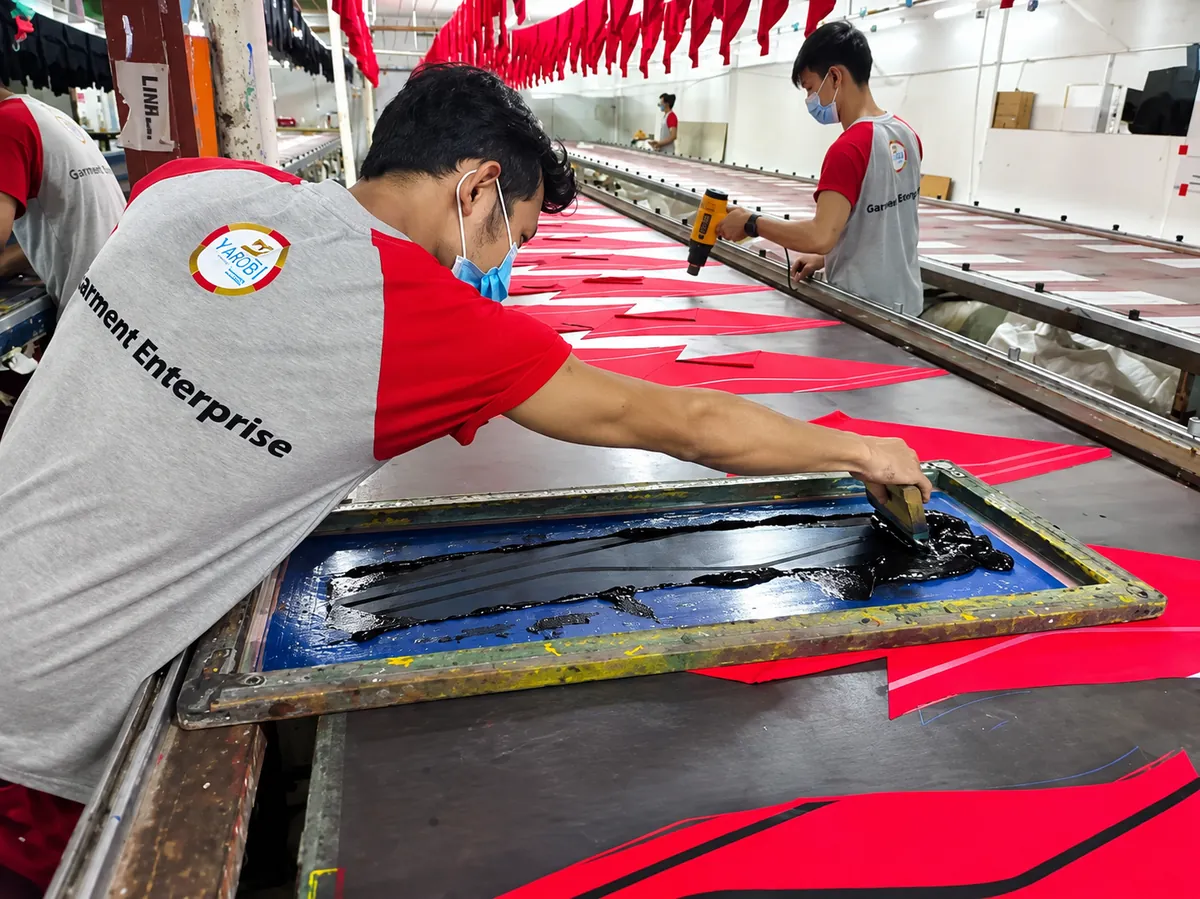 Worker pulling ink across a silk screen